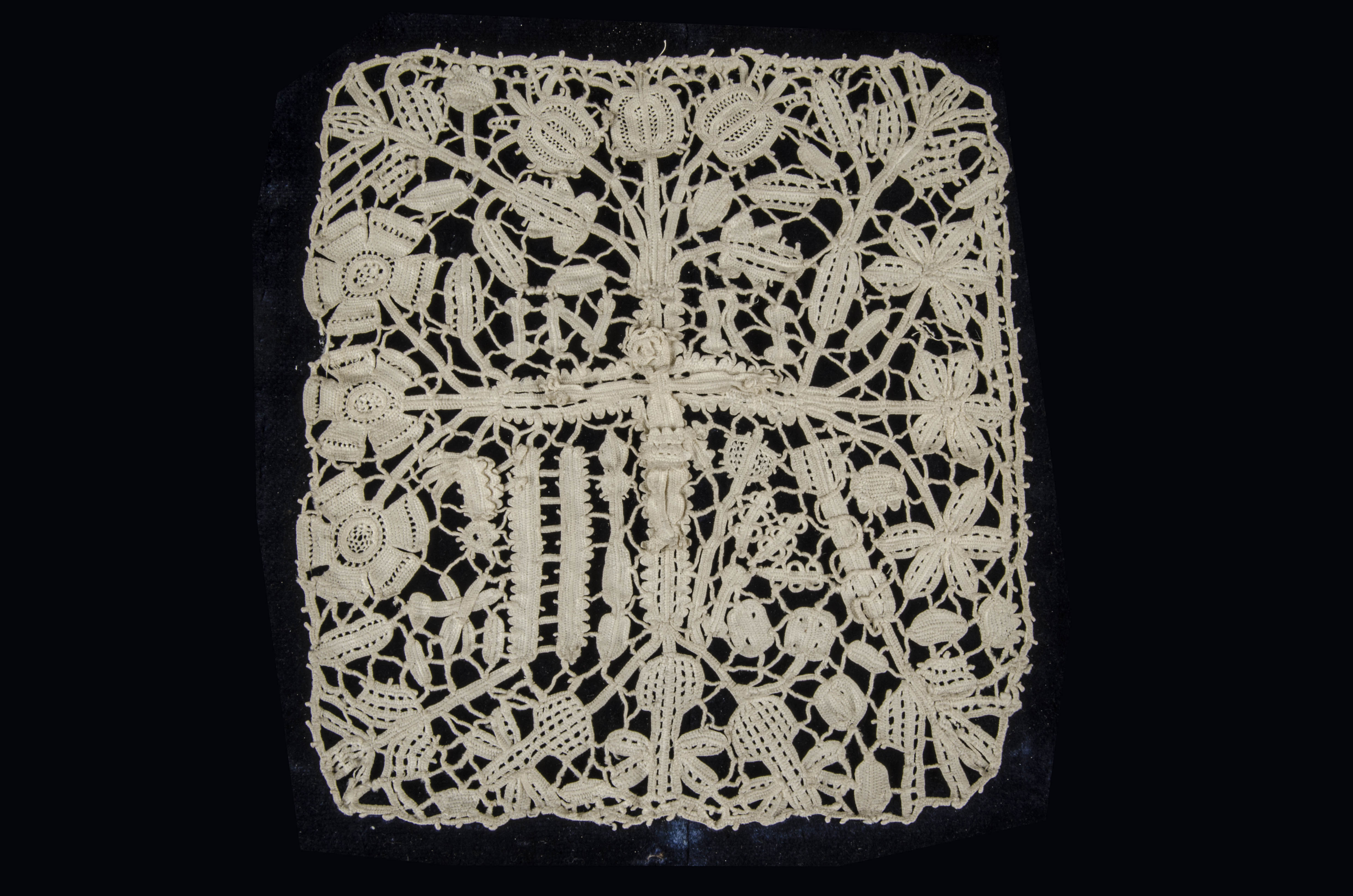 A square of 17th century needle lace, worked with a crucifixion scene among four floral vignettes