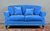 A modern blue velvet upholstered two person sofa, with matching cushions